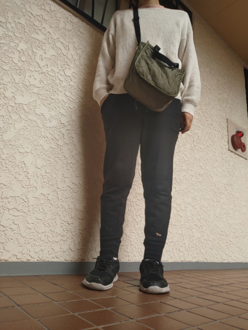 ブラック系のスウェットパンツ、グリーン系のショルダーバッグ、ブラック系のスニーカーを着用したレディースの秋コーディネートの2枚目の写真