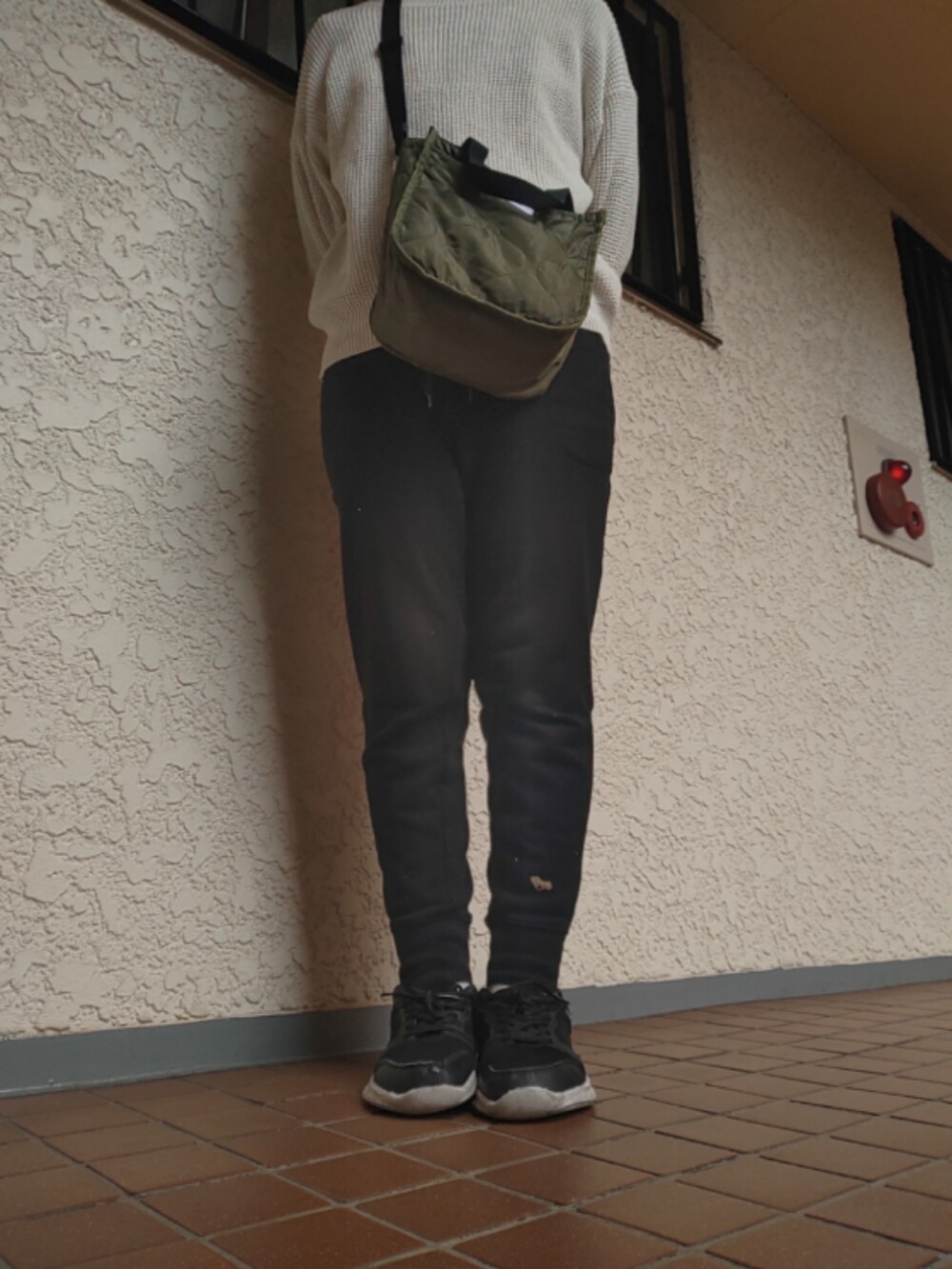 ブラック系のスウェットパンツ、グリーン系のショルダーバッグ、ブラック系のスニーカーを着用したレディースの秋コーディネートの3枚目の写真