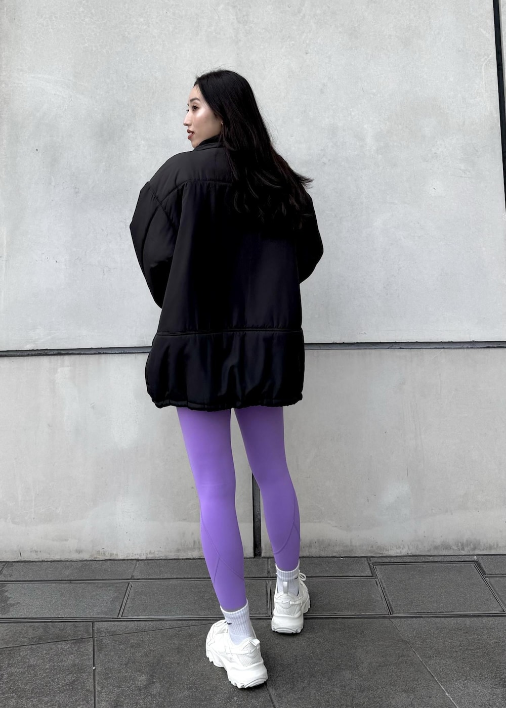 ホワイト系のスニーカー、ブラック系のダウンジャケット/コート、ブラック系のTシャツ/カットソーを着用したレディースの冬コーディネートの2枚目の写真