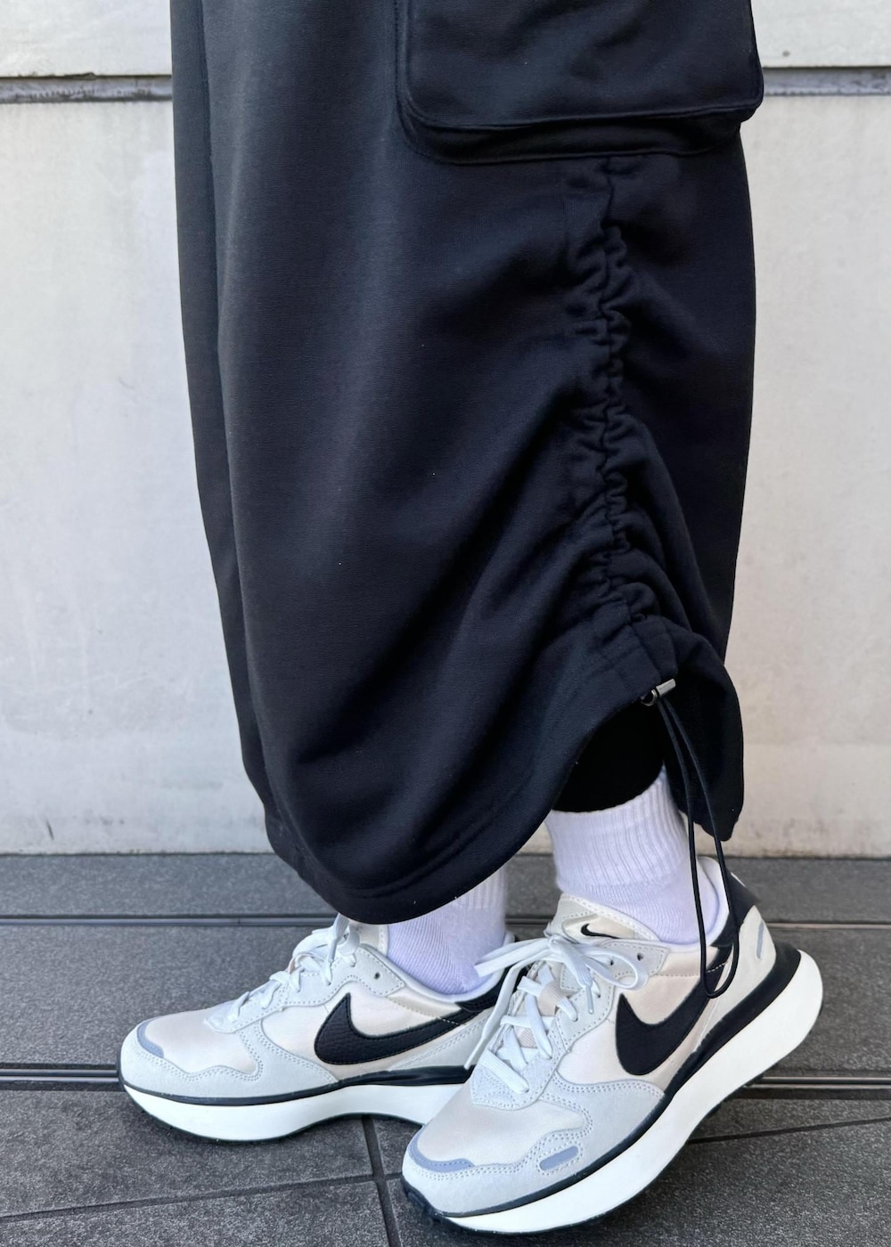 ブラック系のブルゾン、ブラック系のスカート、ホワイト系のスニーカーを着用したレディースの冬コーディネートの7枚目の写真