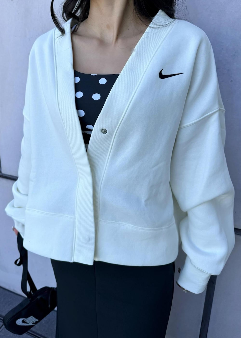 ブラック系のボディバッグ/ウエストポーチ、ホワイト系のカーディガン/ボレロ、ホワイト系のスニーカーを着用したレディースの秋コーディネートの6枚目の写真