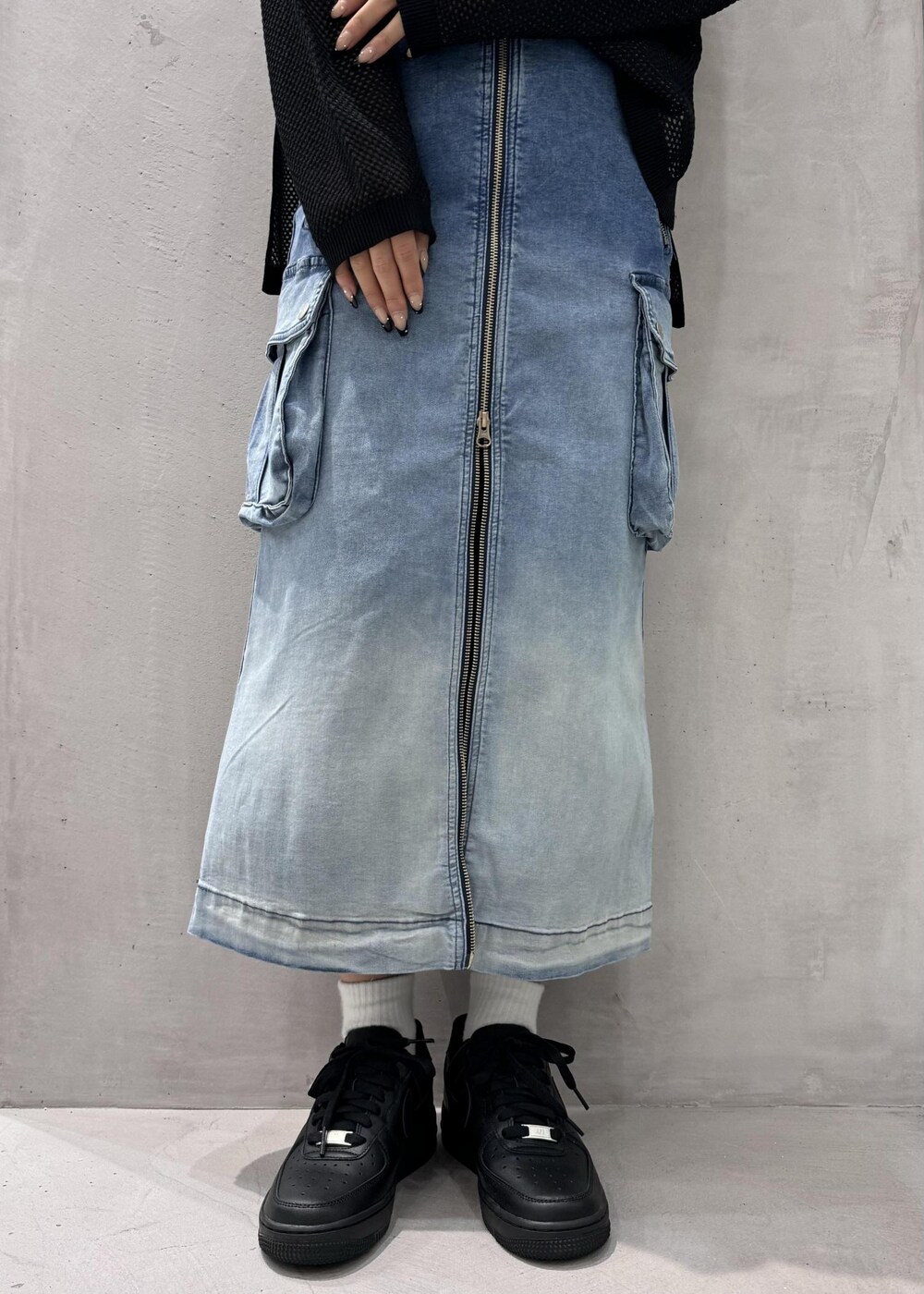 ブラック系のスニーカー、ブラック系のTシャツ/カットソー、ブルー系のデニムスカートを着用したレディースの春コーディネートの4枚目の写真