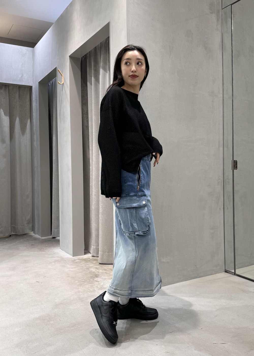 ブラック系のスニーカー、ブラック系のTシャツ/カットソー、ブルー系のデニムスカートを着用したレディースの春コーディネートの2枚目の写真