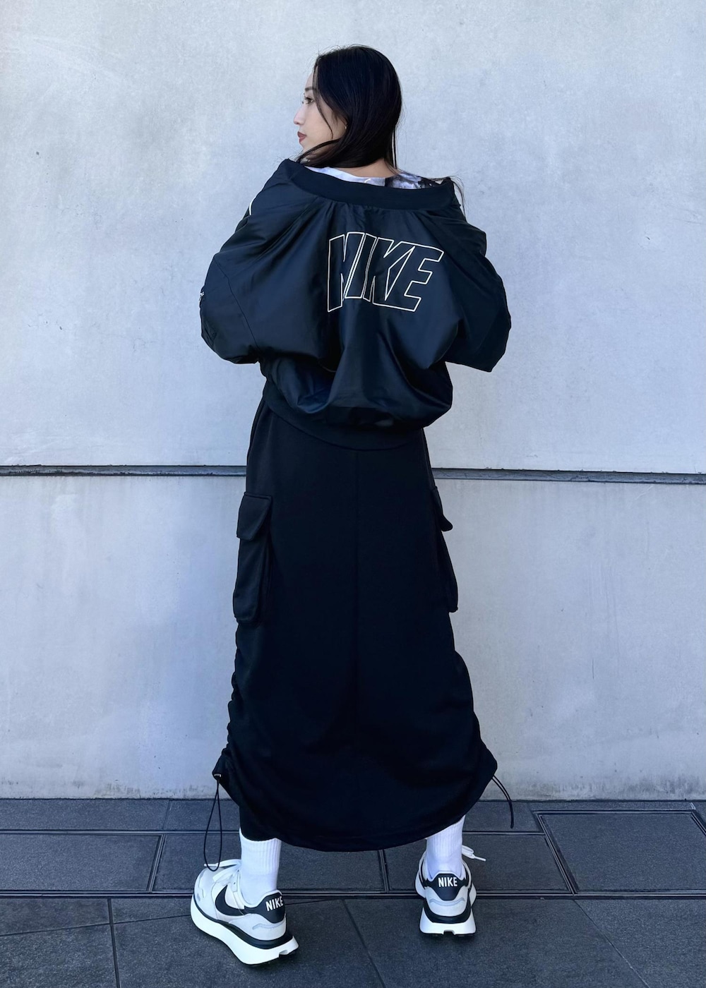 ブラック系のブルゾン、ブラック系のスカート、ホワイト系のスニーカーを着用したレディースの冬コーディネートの2枚目の写真