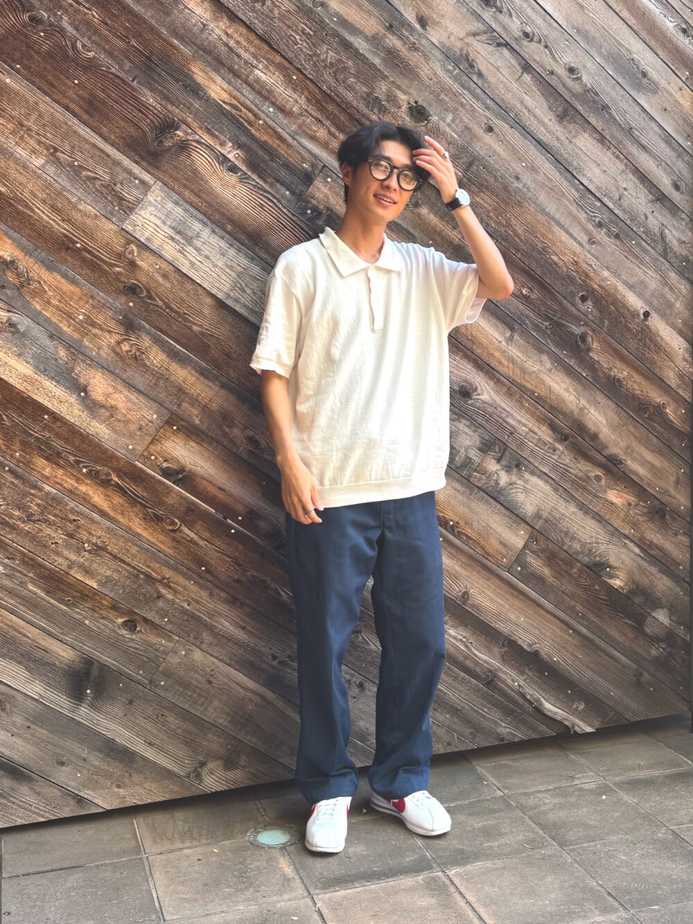ホワイト系のポロシャツ、ブルー系のチノパンツ、ホワイト系のスニーカーを着用したメンズの夏コーディネートの3枚目の写真