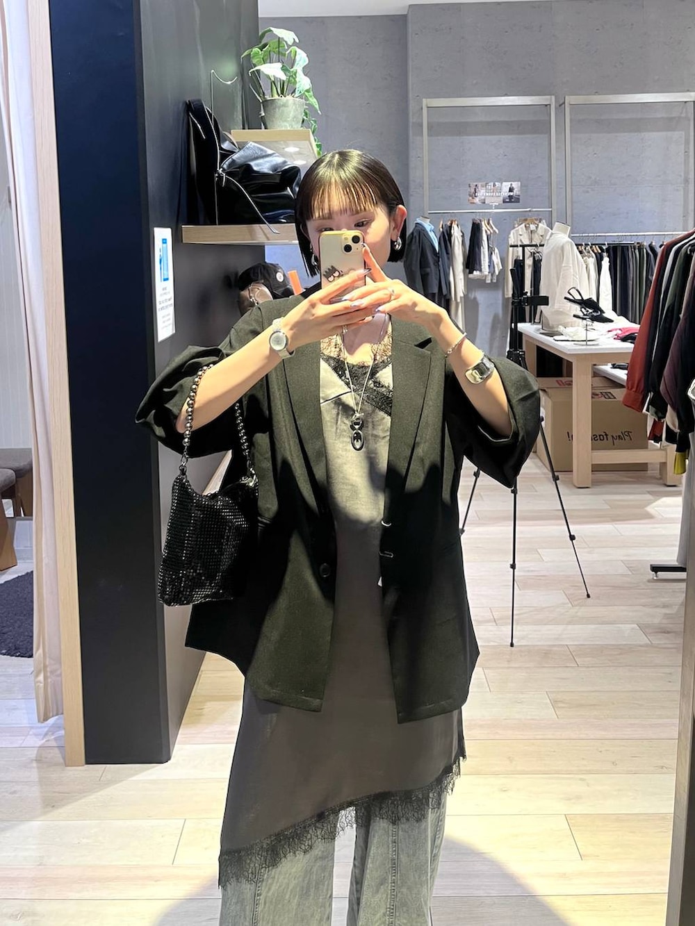 ブラック系のショルダーバッグ、ブルー系のデニムパンツ、シルバー系のネックレスを着用したレディースの春コーディネートの4枚目の写真