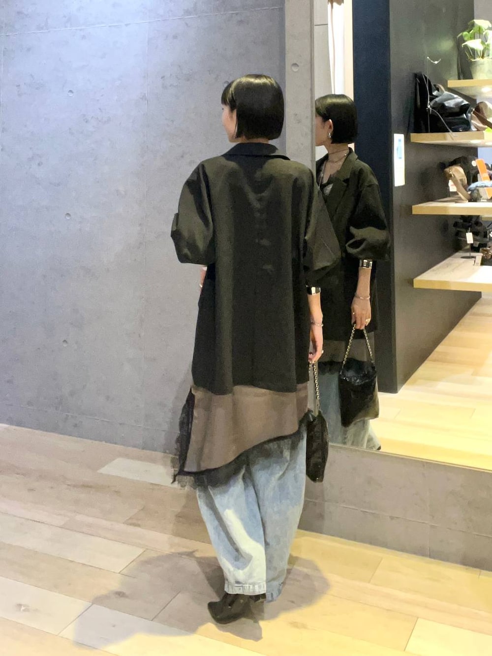 ブラック系のショルダーバッグ、ブルー系のデニムパンツ、シルバー系のネックレスを着用したレディースの春コーディネートの3枚目の写真
