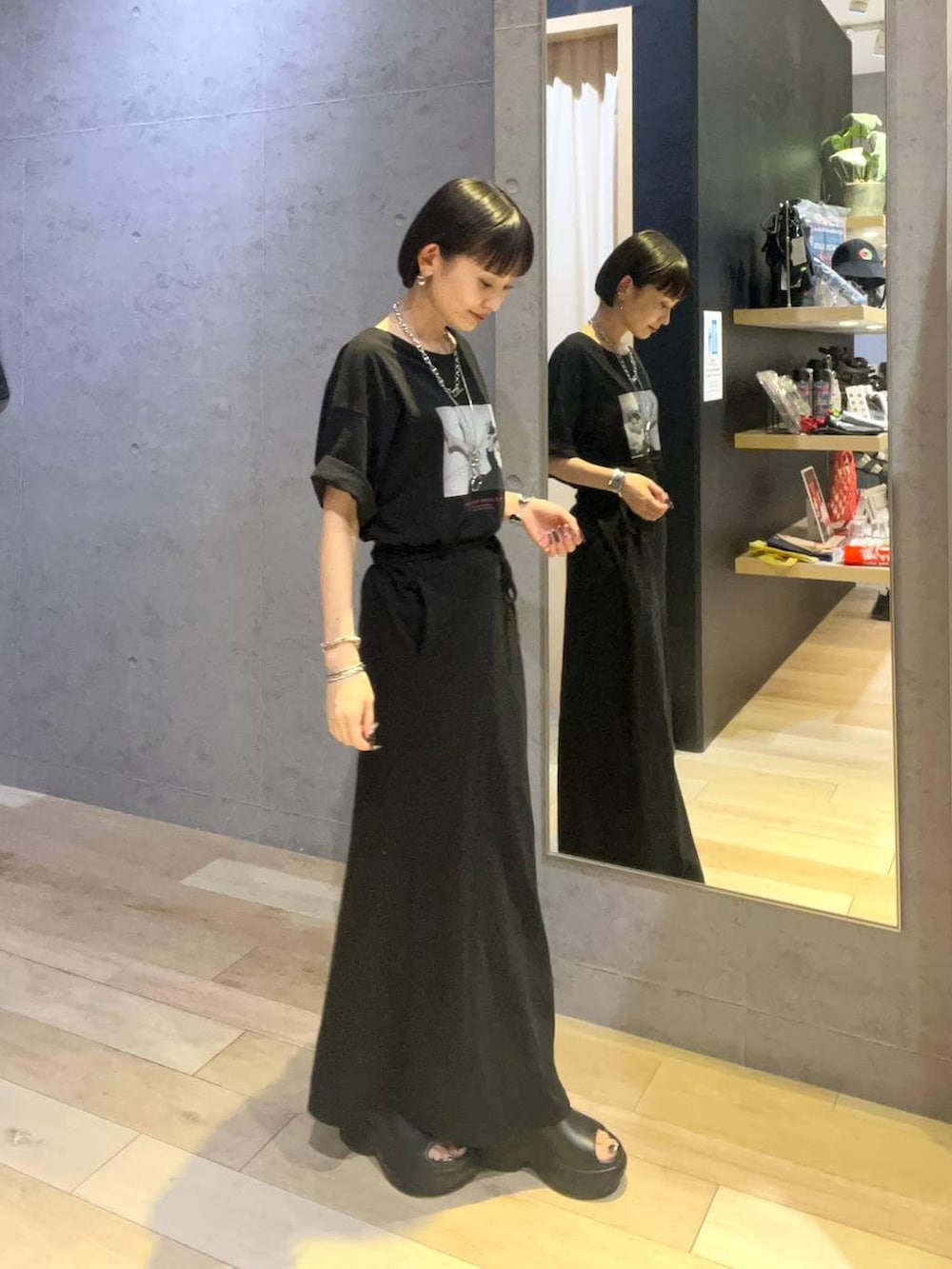 ブラック系のスカート、ブラック系のサンダル、ブラック系のTシャツ/カットソーを着用したレディースの夏コーディネートの2枚目の写真