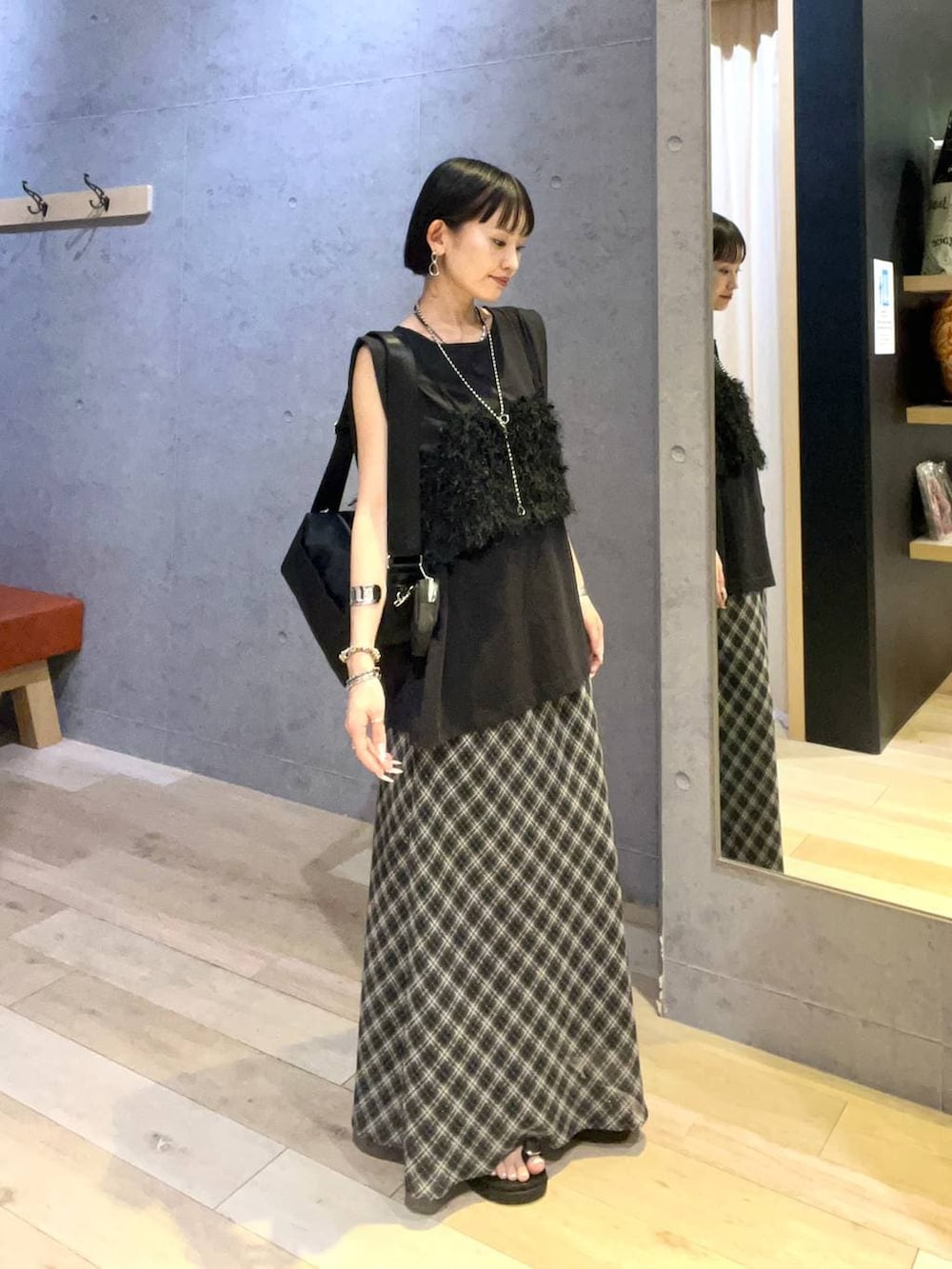 ブラック系のショルダーバッグ、ブラック系のその他トップス、ブラック系のTシャツ/カットソーを着用したレディースの夏コーディネートの2枚目の写真