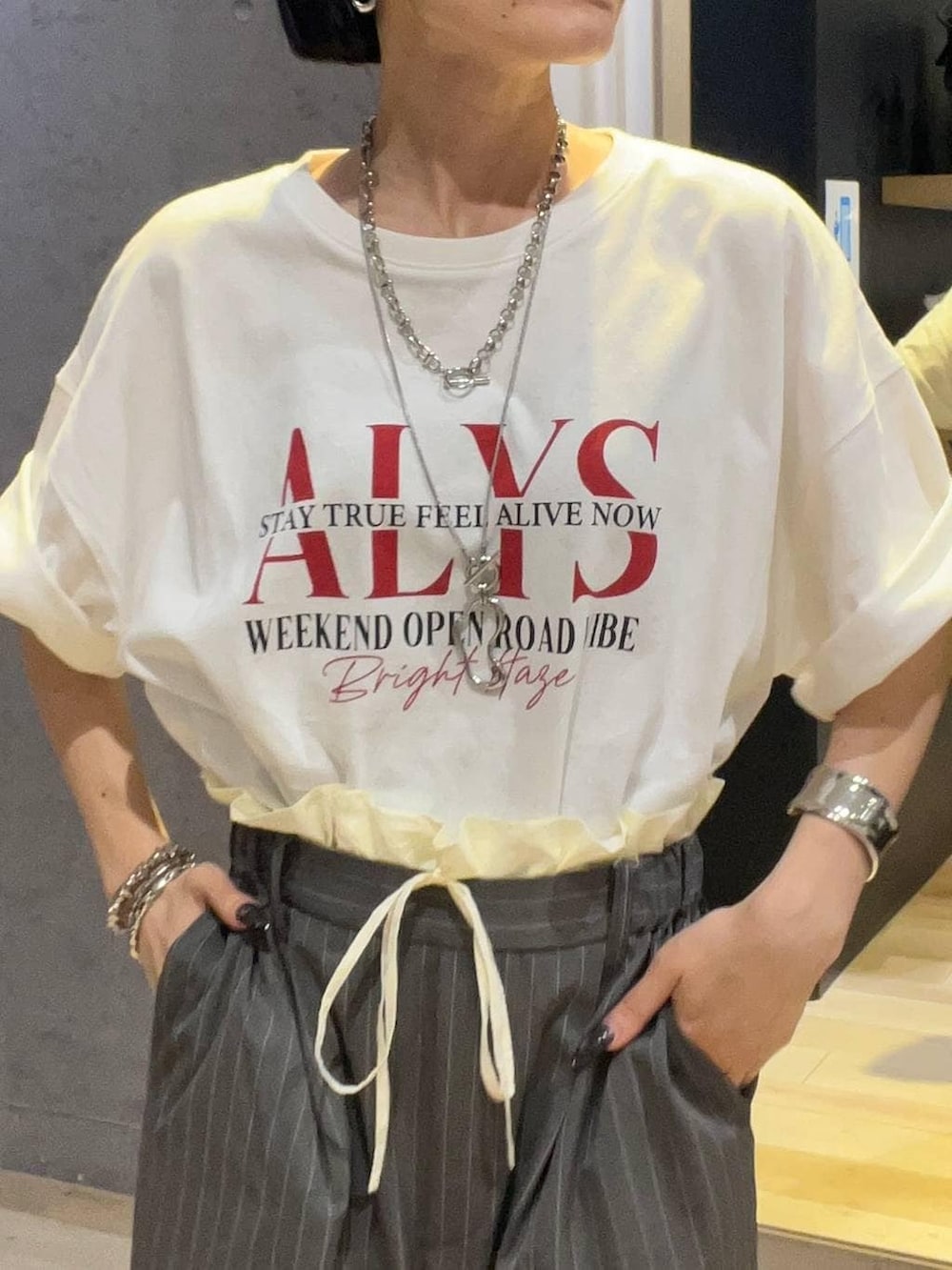 ホワイト系のTシャツ/カットソー、ブラック系のサンダル、その他のブレスレットを着用したレディースの夏コーディネートの4枚目の写真