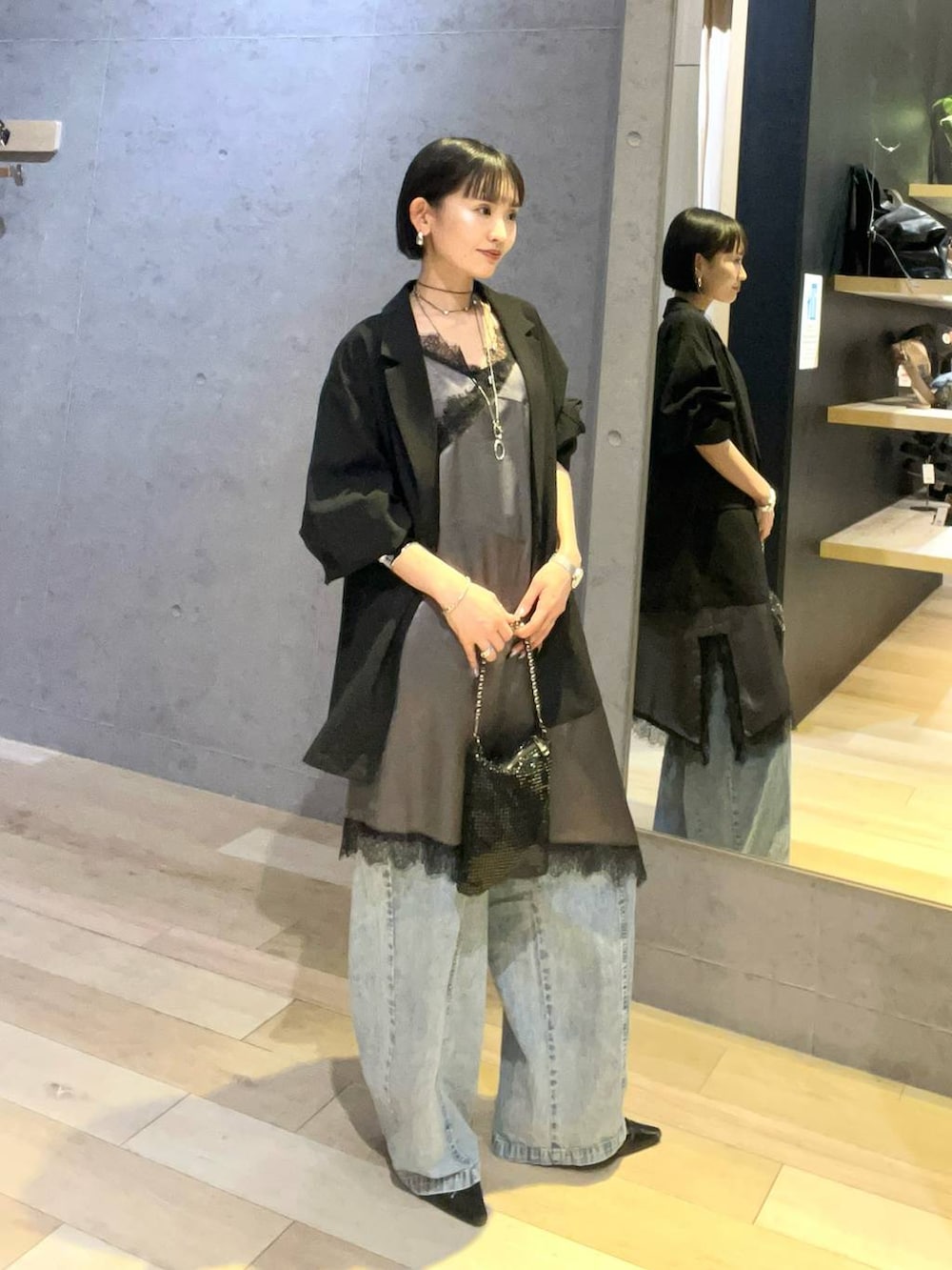 ブラック系のショルダーバッグ、ブルー系のデニムパンツ、シルバー系のネックレスを着用したレディースの春コーディネートの2枚目の写真