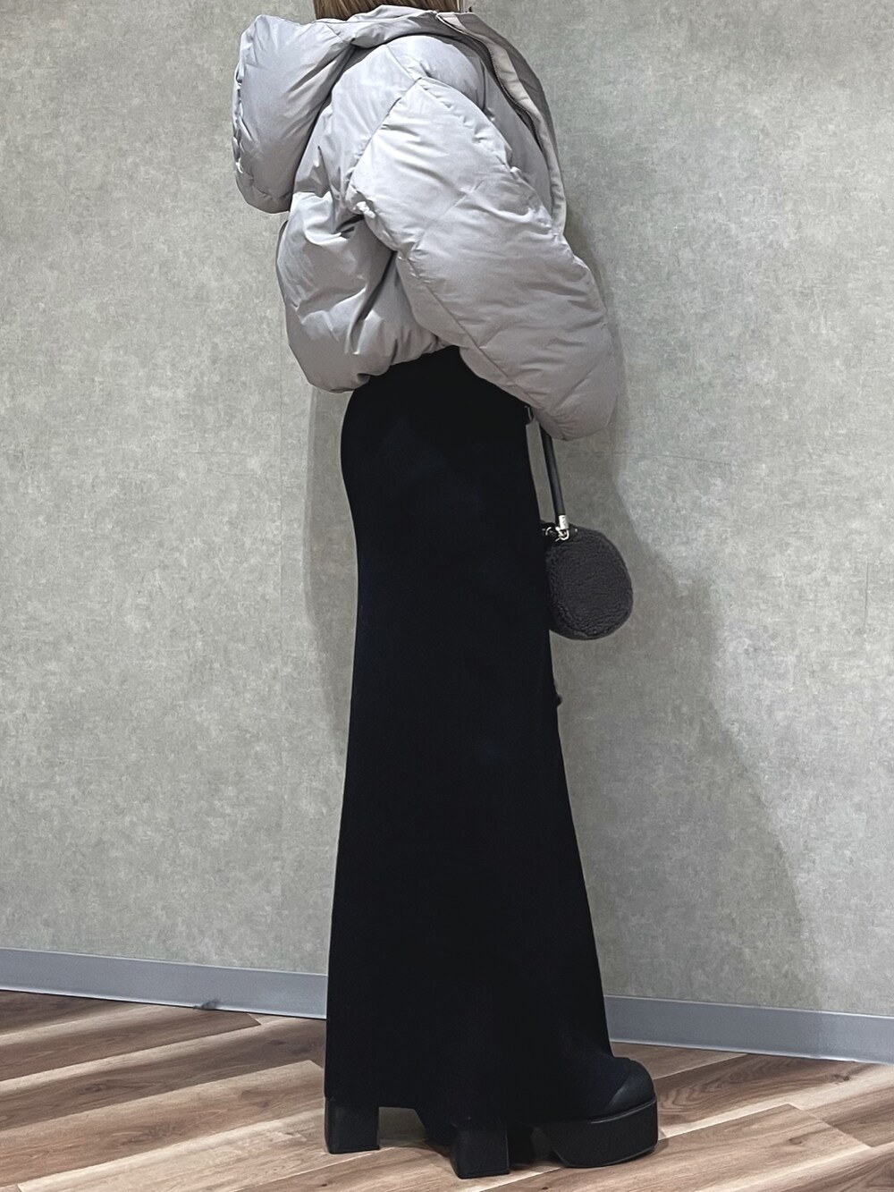 グレー系のダウンジャケット/コート、ホワイト系のハンドバッグ、ブルー系のワンピースを着用したレディースの冬コーディネートの2枚目の写真