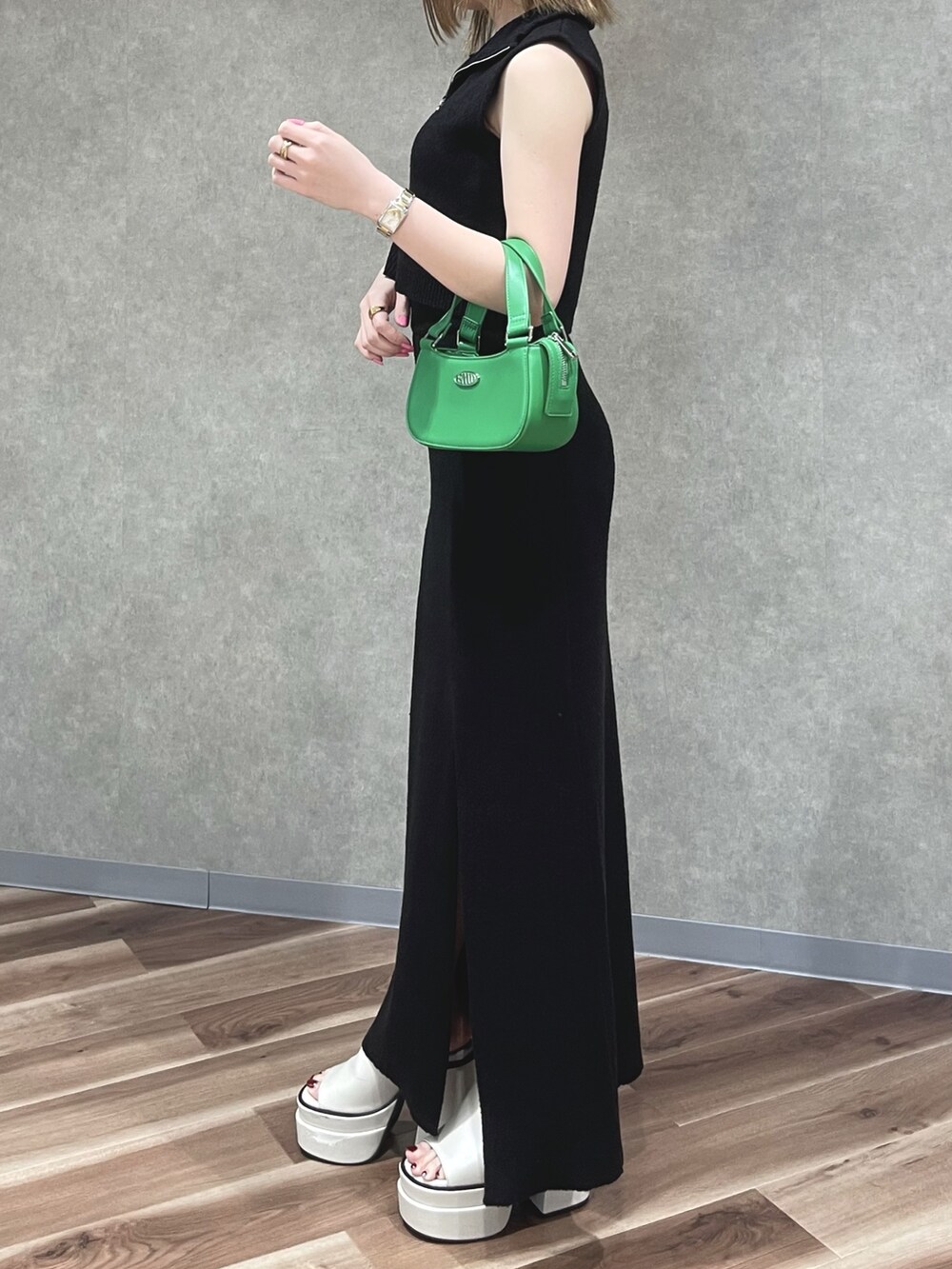 ブラック系のタンクトップ、ブラック系のスカート、グリーン系のハンドバッグを着用したレディースの夏コーディネートの2枚目の写真