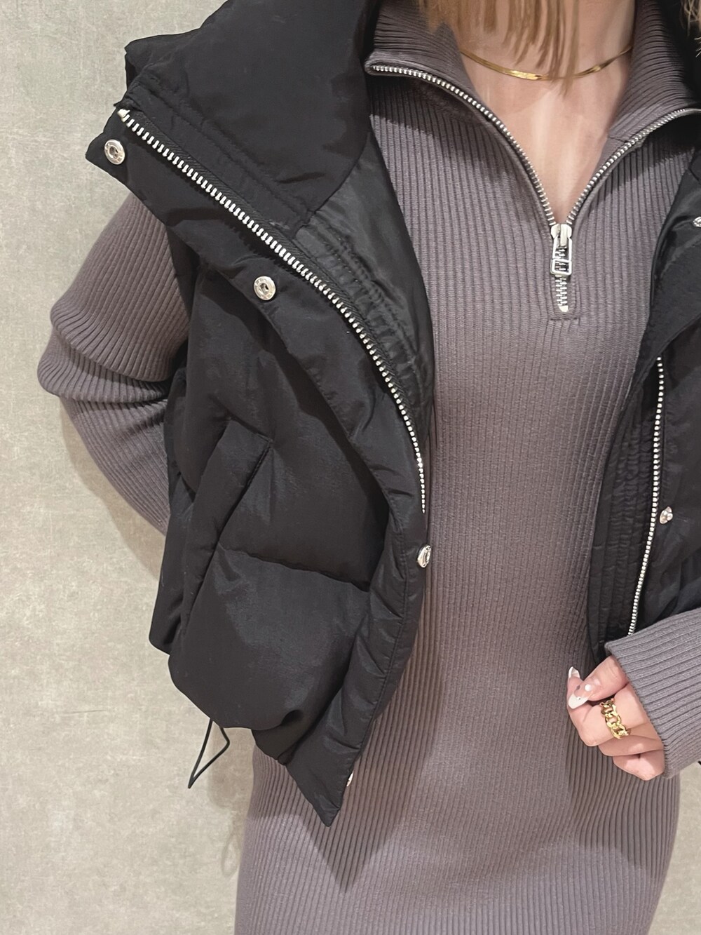 ブラック系のダウンベスト、グレー系のワンピース、ブラック系のブーツを着用したレディースの秋コーディネートの4枚目の写真