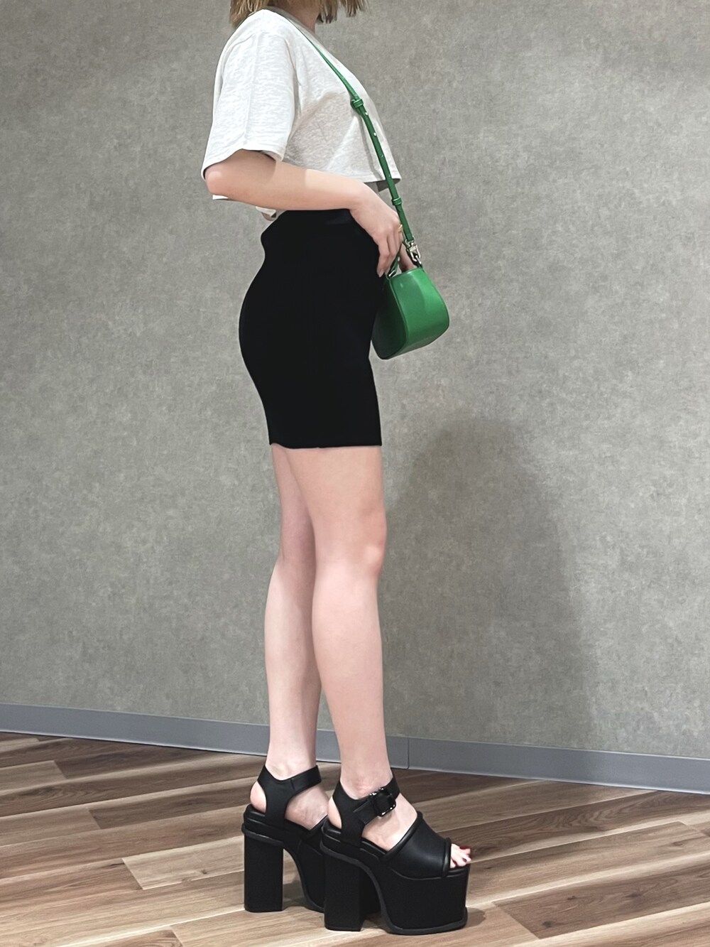 グレー系のTシャツ/カットソー、グリーン系のハンドバッグ、ブラック系のスカートを着用したレディースの春コーディネートの2枚目の写真