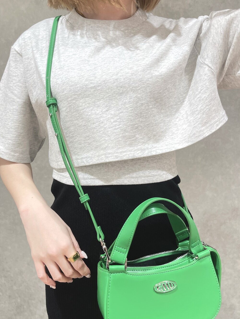 グレー系のTシャツ/カットソー、グリーン系のハンドバッグ、ブラック系のスカートを着用したレディースの春コーディネートの4枚目の写真