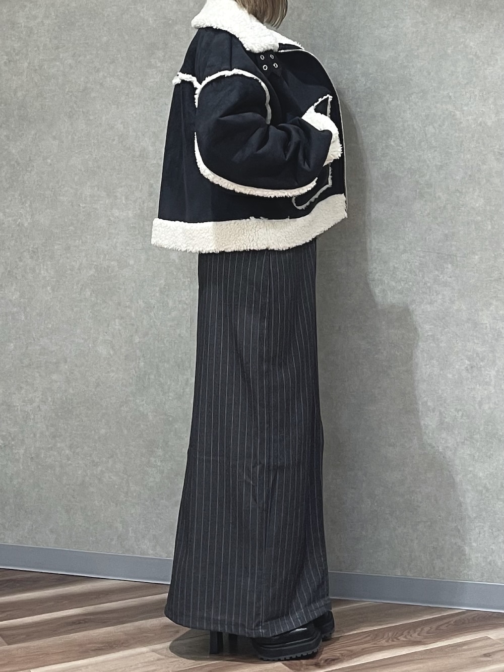 ホワイト系のニット/セーター、グレー系のスカート、ブラック系のブーツを着用したレディースの冬コーディネートの2枚目の写真