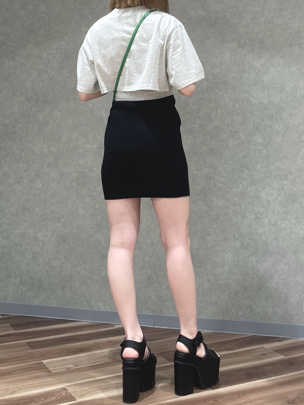 グレー系のTシャツ/カットソー、グリーン系のハンドバッグ、ブラック系のスカートを着用したレディースの春コーディネートの3枚目の写真