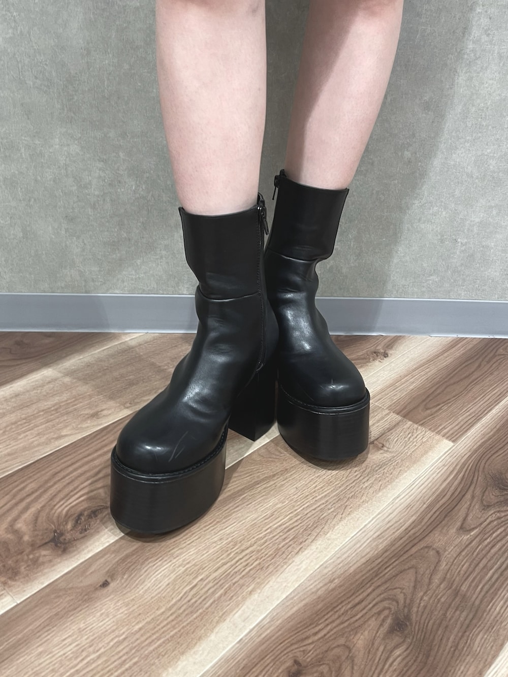 ブラック系のダウンベスト、グレー系のワンピース、ブラック系のブーツを着用したレディースの秋コーディネートの5枚目の写真