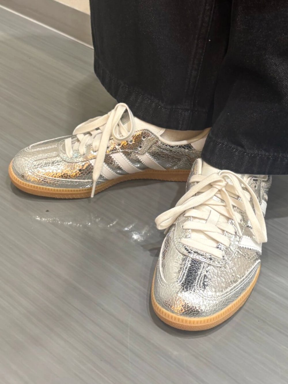 シルバー系のスニーカー、ブラック系のデニムパンツ、ホワイト系のポロシャツを着用したレディースの秋コーディネートの6枚目の写真