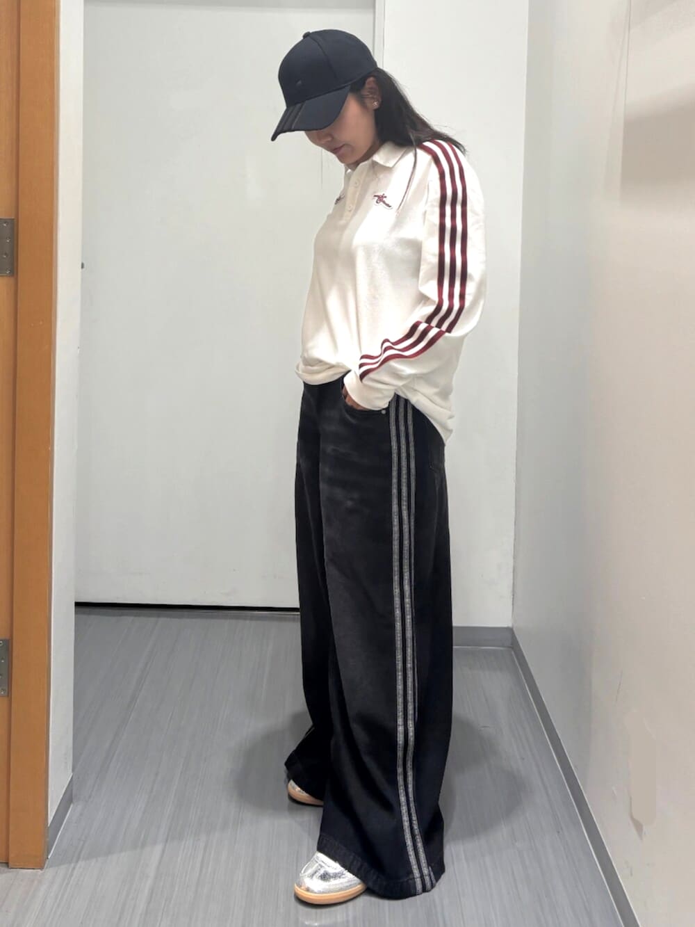 シルバー系のスニーカー、ブラック系のデニムパンツ、ホワイト系のポロシャツを着用したレディースの秋コーディネートの2枚目の写真