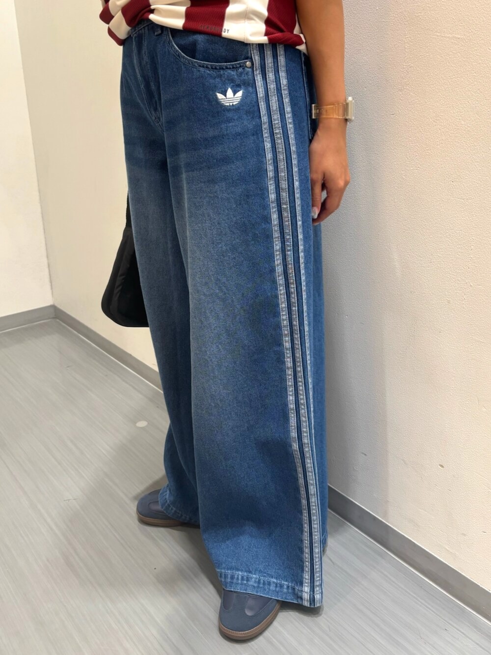 レッド系のトップス、ブルー系のデニムパンツ、ブルー系のスニーカーを着用したレディースの夏コーディネートの3枚目の写真