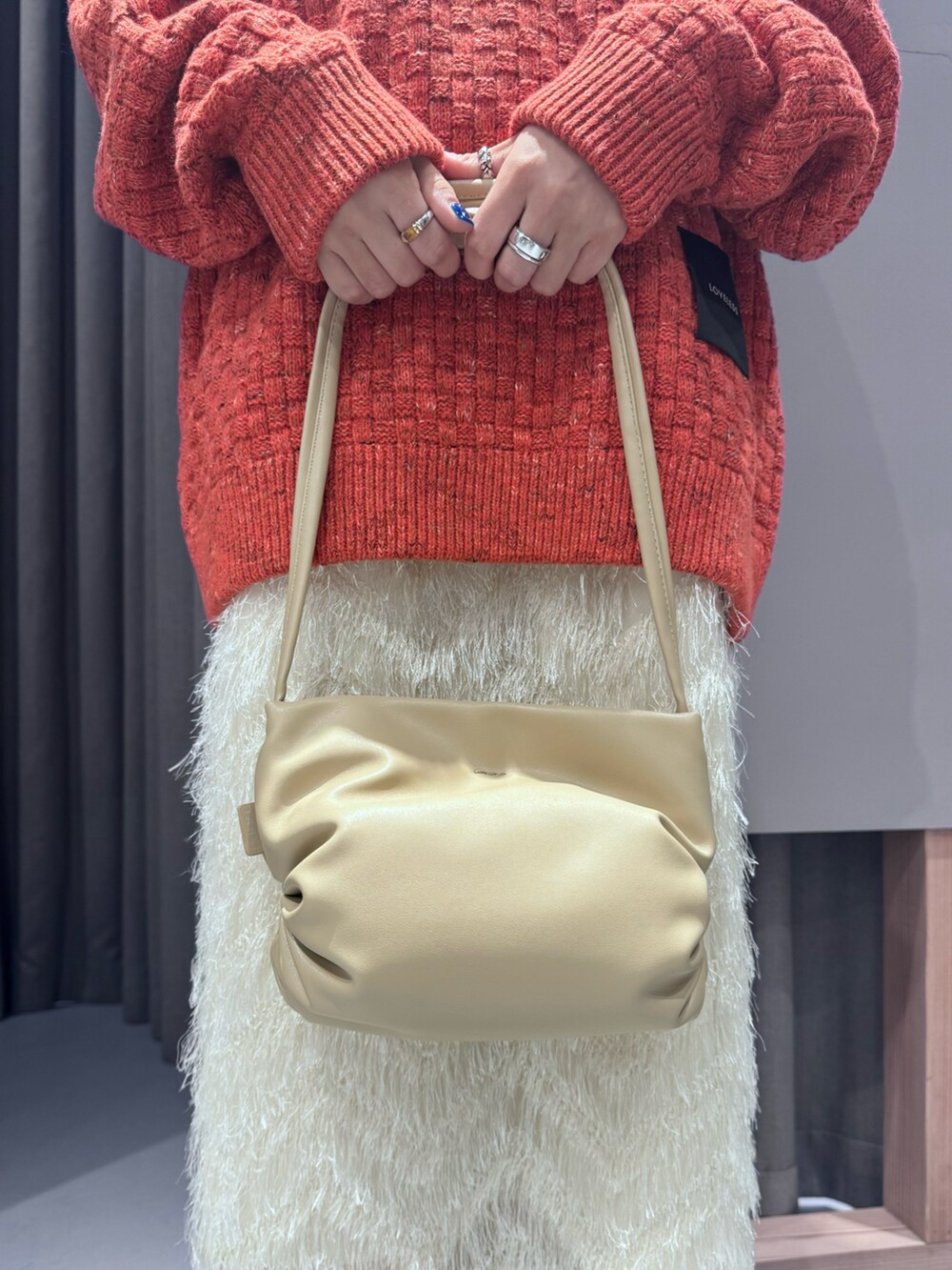 レッド系のニット/セーター、ホワイト系のスカートを着用したレディースの秋コーディネートの4枚目の写真