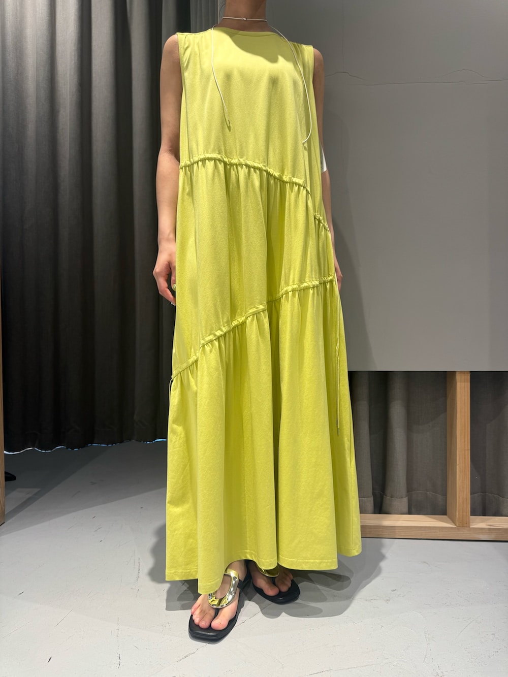 イエロー系のワンピース、ベージュ系のシャツ/ブラウス、ホワイト系のネックレスを着用したレディースの春コーディネートの4枚目の写真