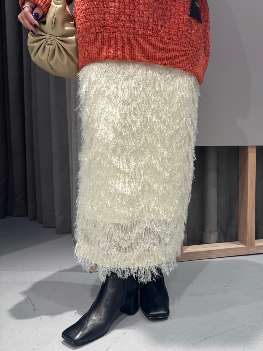 レッド系のニット/セーター、ホワイト系のスカートを着用したレディースの秋コーディネートの3枚目の写真