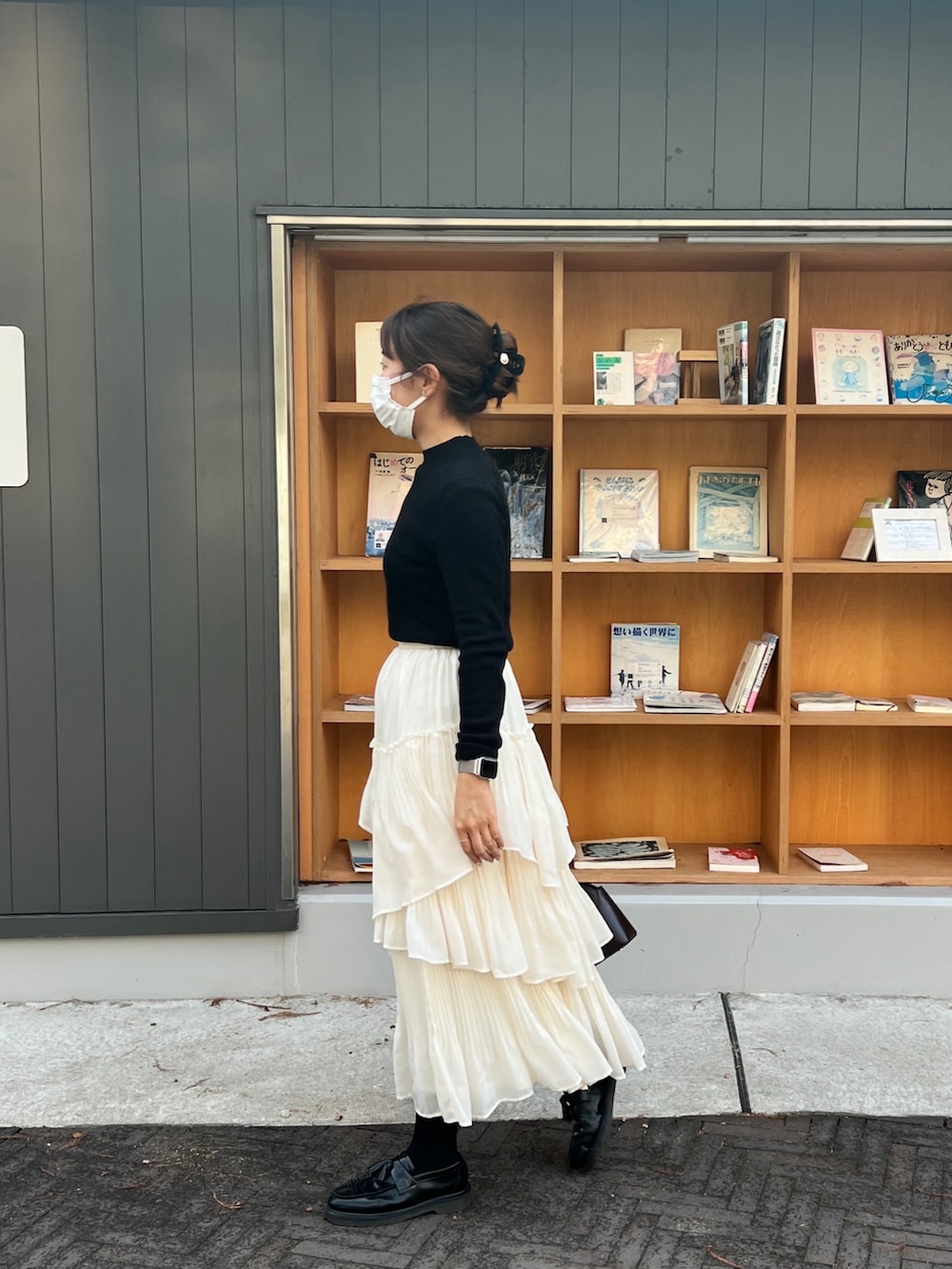 ブラック系のニット/セーター、ホワイト系のスカート、レッド系のハンドバッグを着用したレディースの冬コーディネートの2枚目の写真