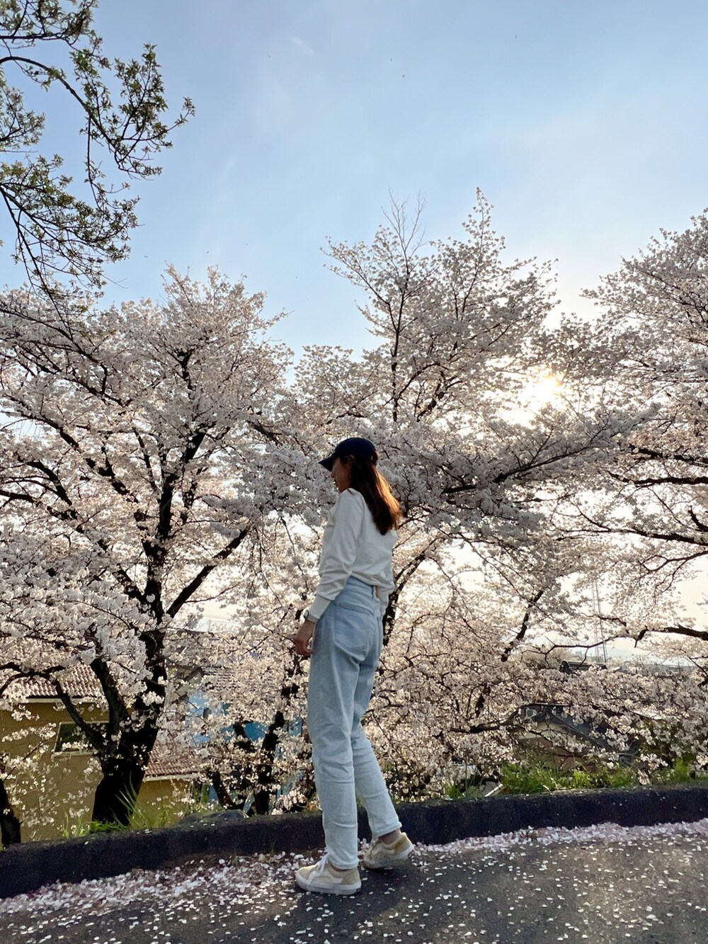 ブルー系のデニムパンツ、ベージュ系のスニーカー、ホワイト系のカーディガン/ボレロを着用したレディースの春コーディネートの2枚目の写真