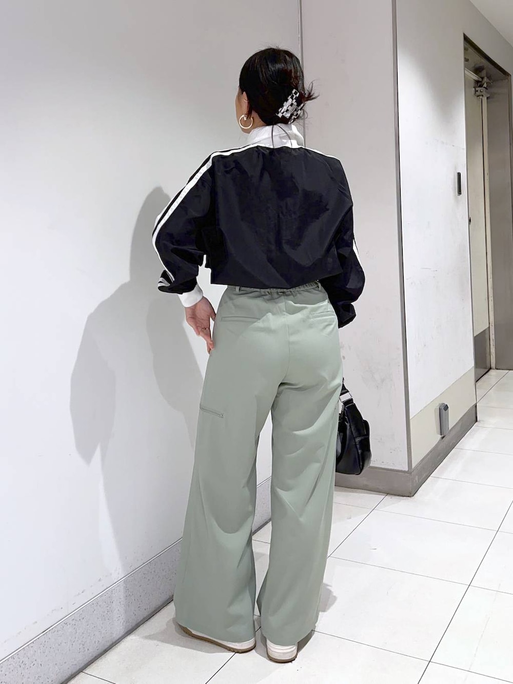 ブラック系のショルダーバッグ、グリーン系のその他パンツ、ブラック系のブルゾンを着用したレディースの冬コーディネートの3枚目の写真