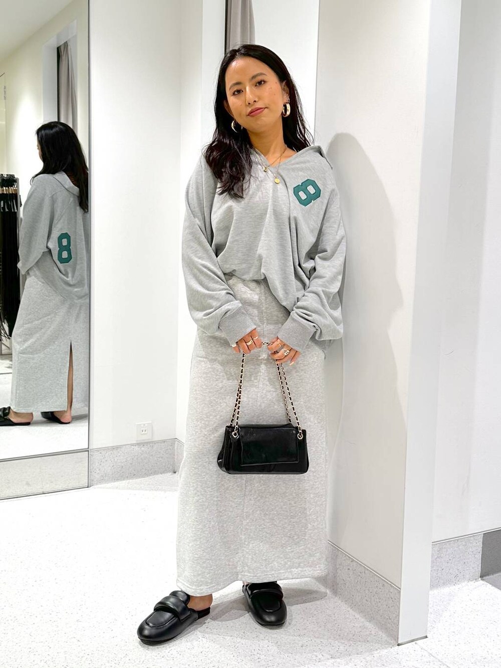 グレー系のスウェット、ブラック系のハンドバッグ、グレー系のスカートを着用したレディースの冬コーディネートの2枚目の写真