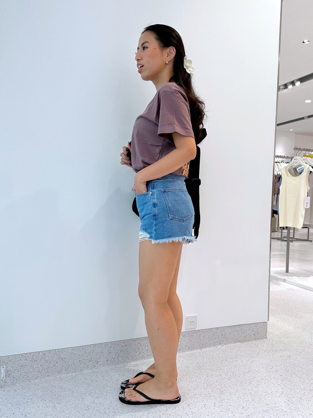 ブルー系のデニムパンツ、ブラック系のバックパック/リュック、ブラウン系のTシャツ/カットソーを着用したレディースの夏コーディネートの4枚目の写真