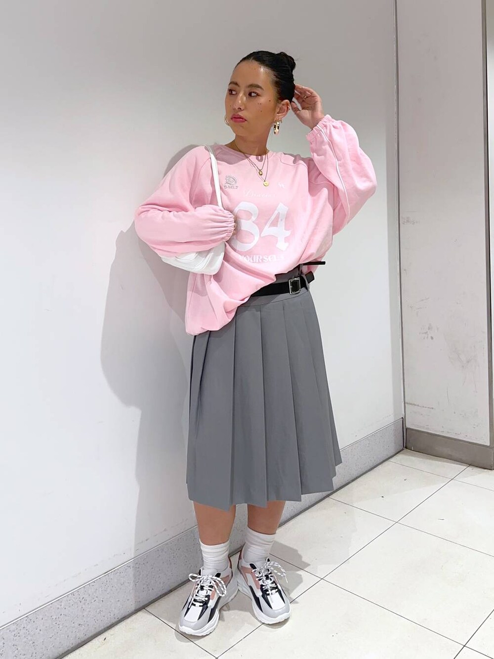 ピンク系のスウェット、グレー系のスカート、ピンク系のスニーカーを着用したレディースの春コーディネートの2枚目の写真