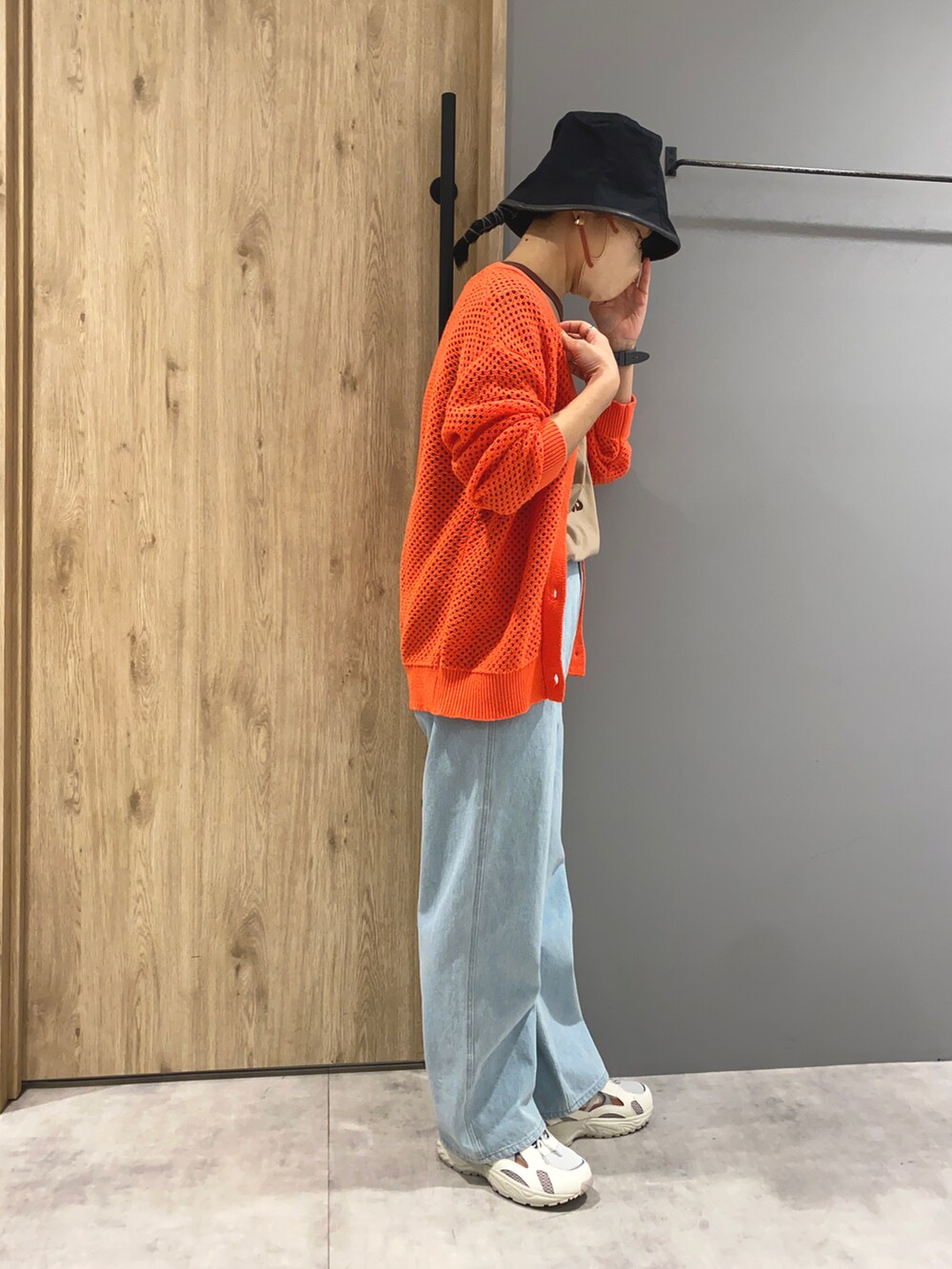 ブラウン系のTシャツ/カットソー、オレンジ系のカーディガン/ボレロ、ブルー系のデニムパンツを着用したレディースの春コーディネートの2枚目の写真
