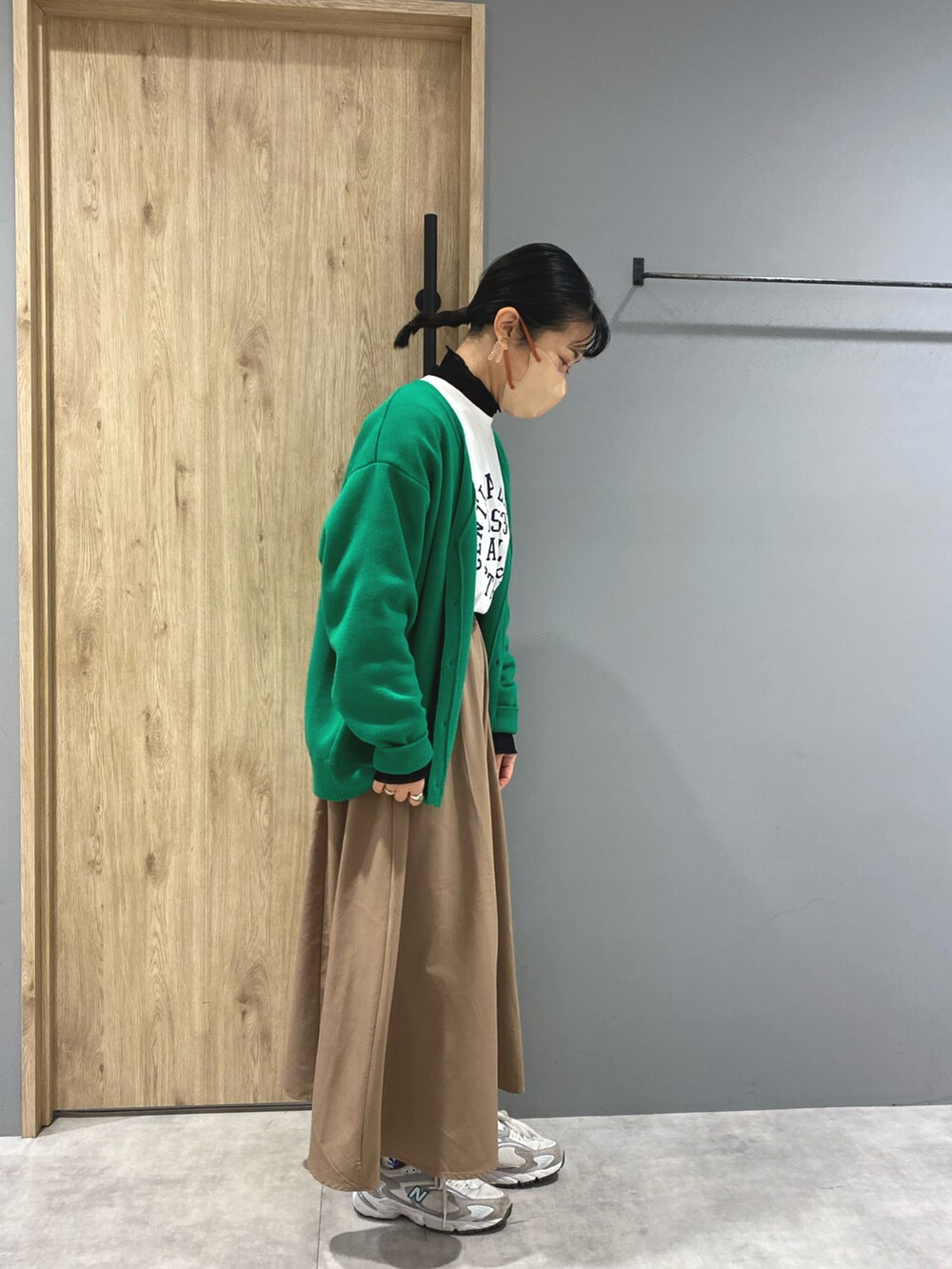 ホワイト系のTシャツ/カットソー、ブラック系のスカート、グリーン系のカーディガン/ボレロを着用したレディースの冬コーディネートの3枚目の写真