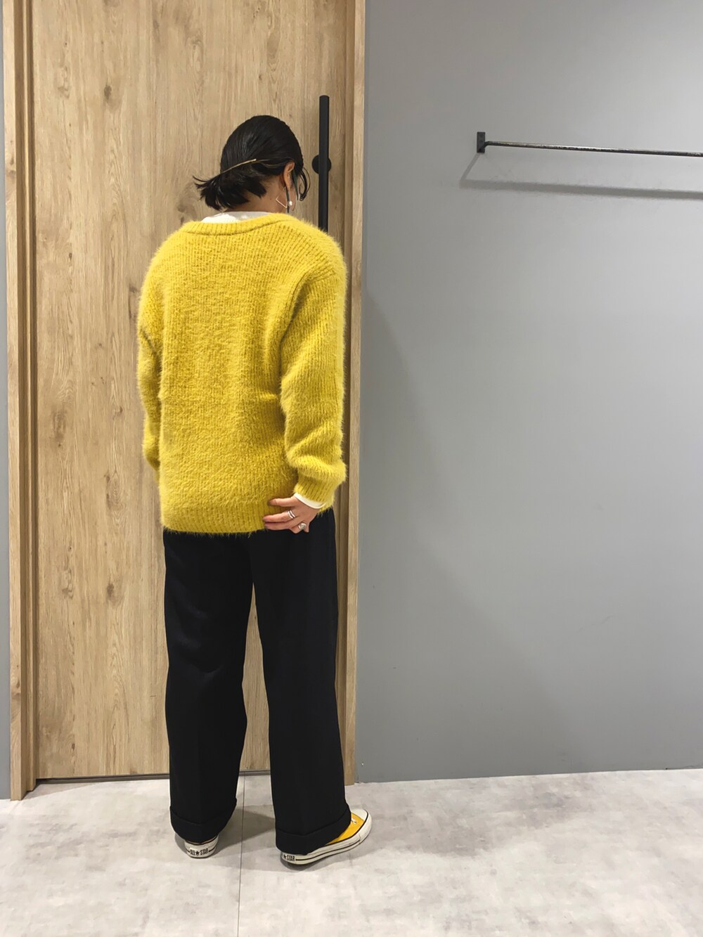 イエロー系のニット/セーター、ホワイト系のTシャツ/カットソー、ブラック系のパンツを着用したレディースの秋コーディネートの3枚目の写真