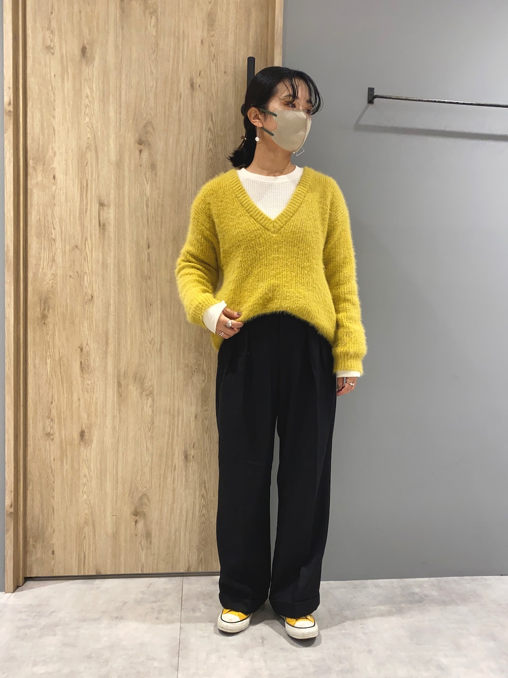 イエロー系のニット/セーター、ホワイト系のTシャツ/カットソー、ブラック系のパンツを着用したレディースの秋コーディネートの2枚目の写真