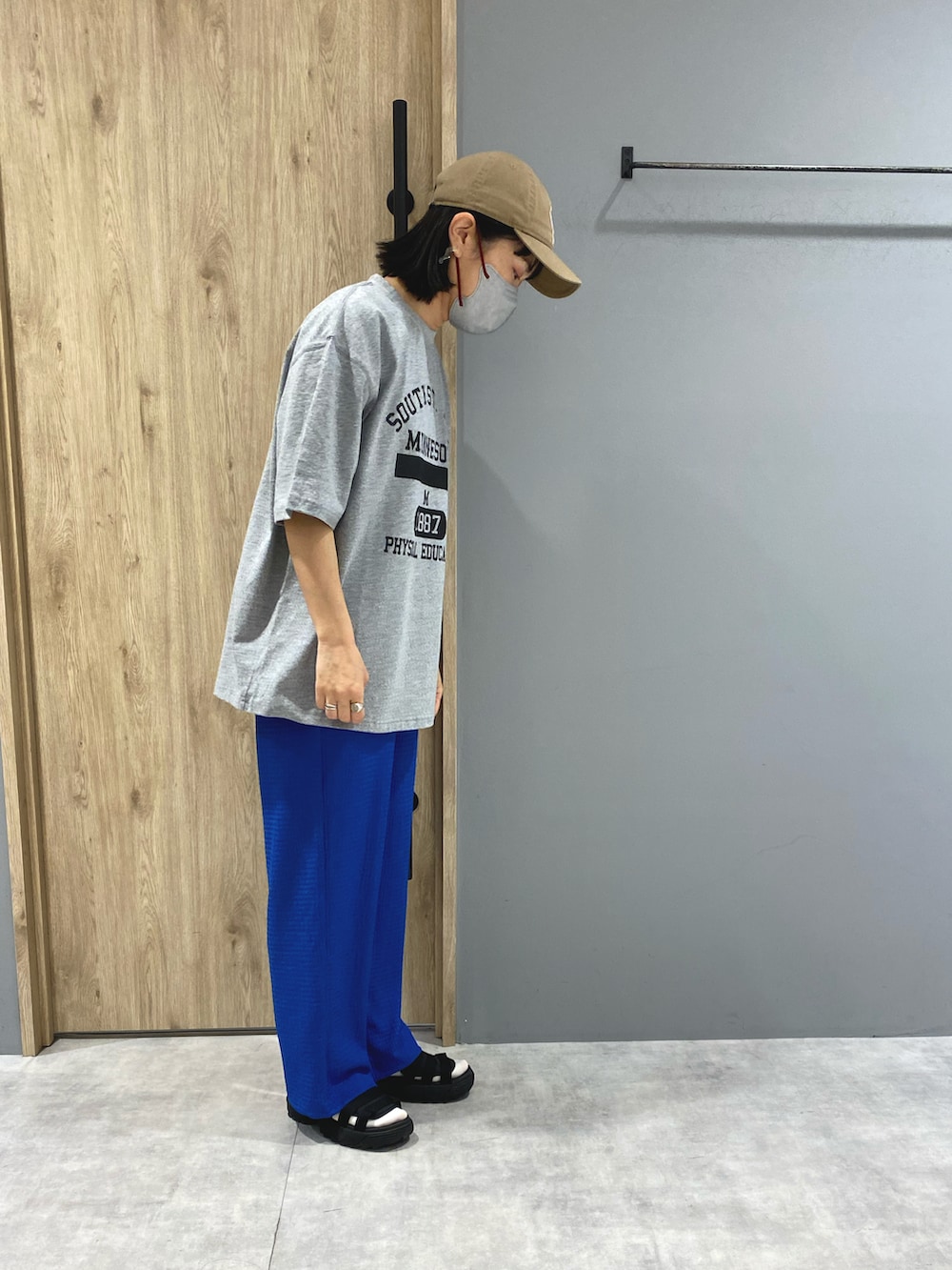 ブルー系のパンツ、グレー系のTシャツ/カットソー、ブラック系のサンダルを着用したレディースの春コーディネートの2枚目の写真