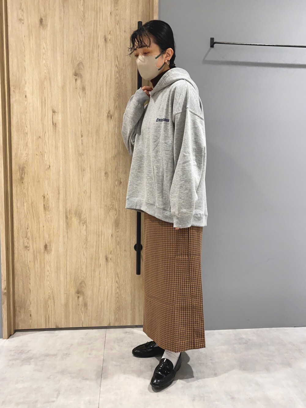 グレー系のパーカー、ブラウン系のスカート、ブラック系のローファーを着用したレディースの冬コーディネートの2枚目の写真