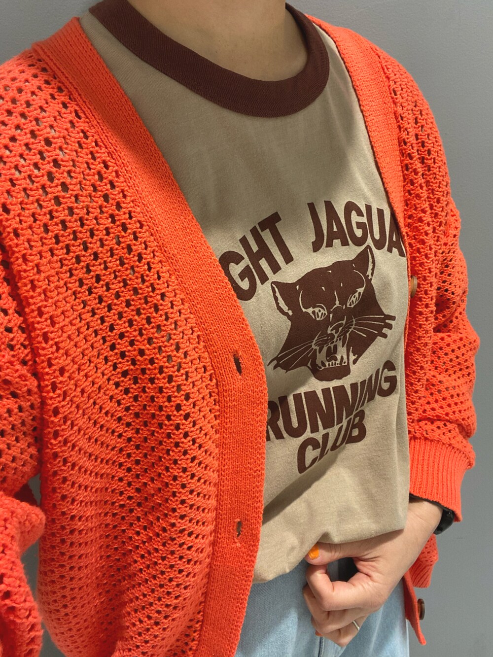 ブラウン系のTシャツ/カットソー、オレンジ系のカーディガン/ボレロ、ブルー系のデニムパンツを着用したレディースの春コーディネートの4枚目の写真