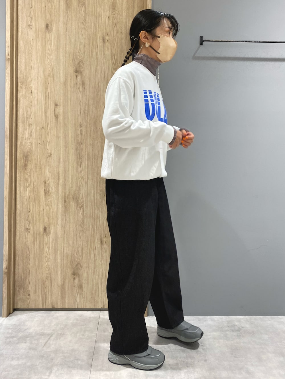 ブラック系のデニムパンツ、グレー系のスニーカー、ホワイト系のスウェットを着用したレディースの秋コーディネートの2枚目の写真