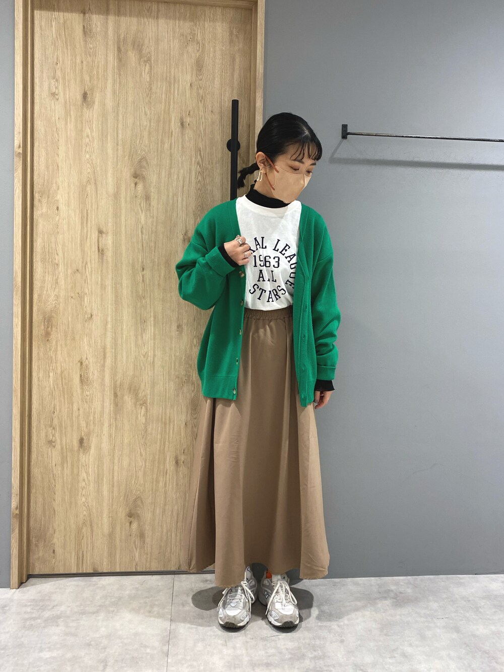 ホワイト系のTシャツ/カットソー、ブラック系のスカート、グリーン系のカーディガン/ボレロを着用したレディースの冬コーディネートの2枚目の写真