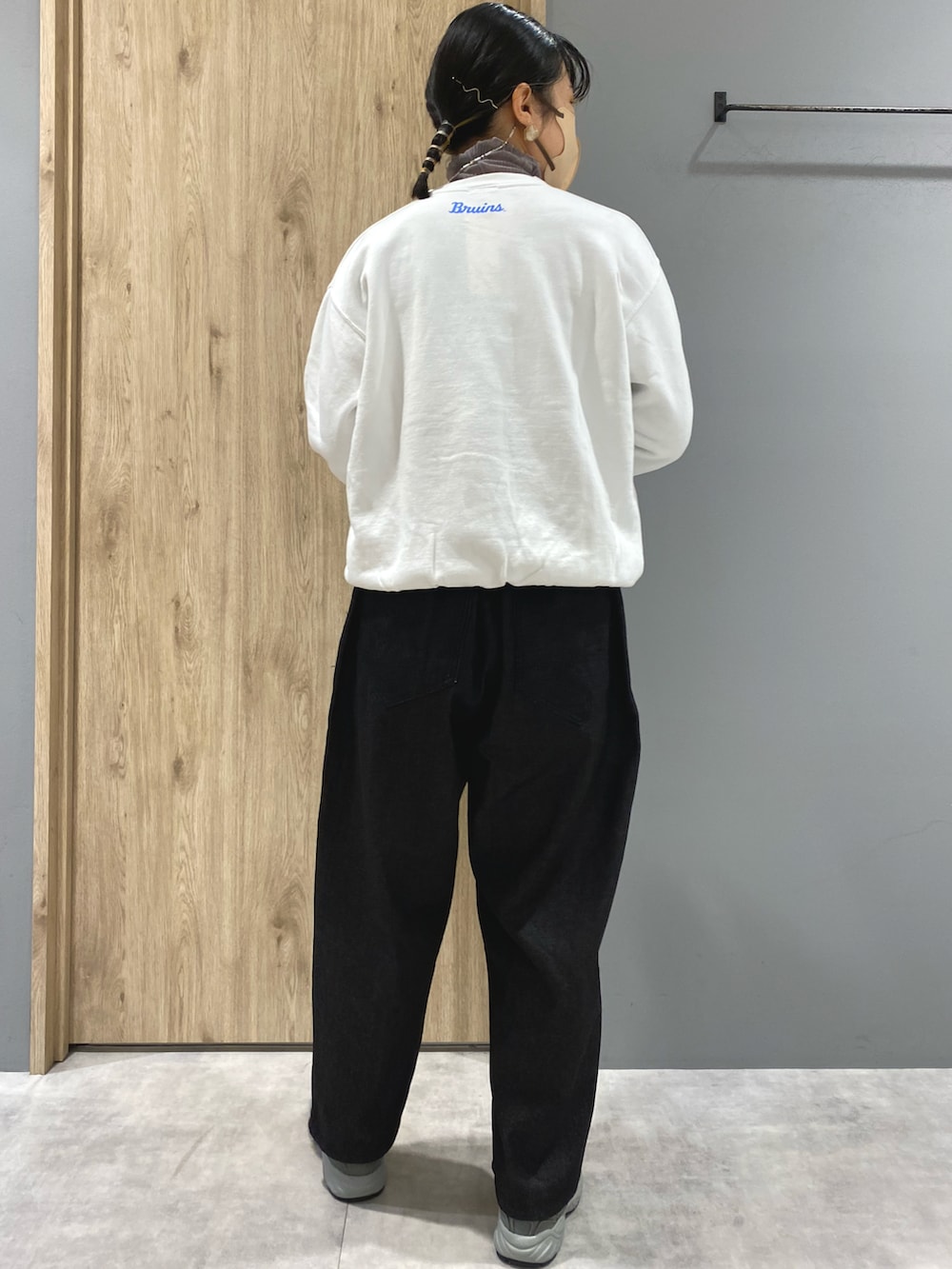 ブラック系のデニムパンツ、グレー系のスニーカー、ホワイト系のスウェットを着用したレディースの秋コーディネートの3枚目の写真