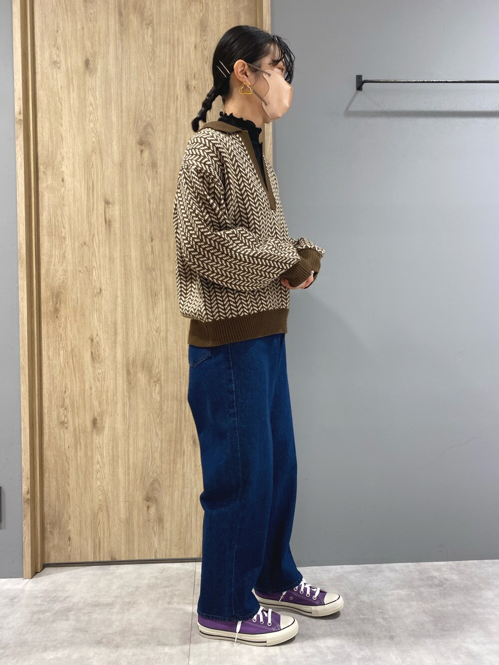 ブルー系のデニムパンツ、ブラウン系のニット/セーター、パープル系のスニーカーを着用したレディースの秋コーディネートの2枚目の写真