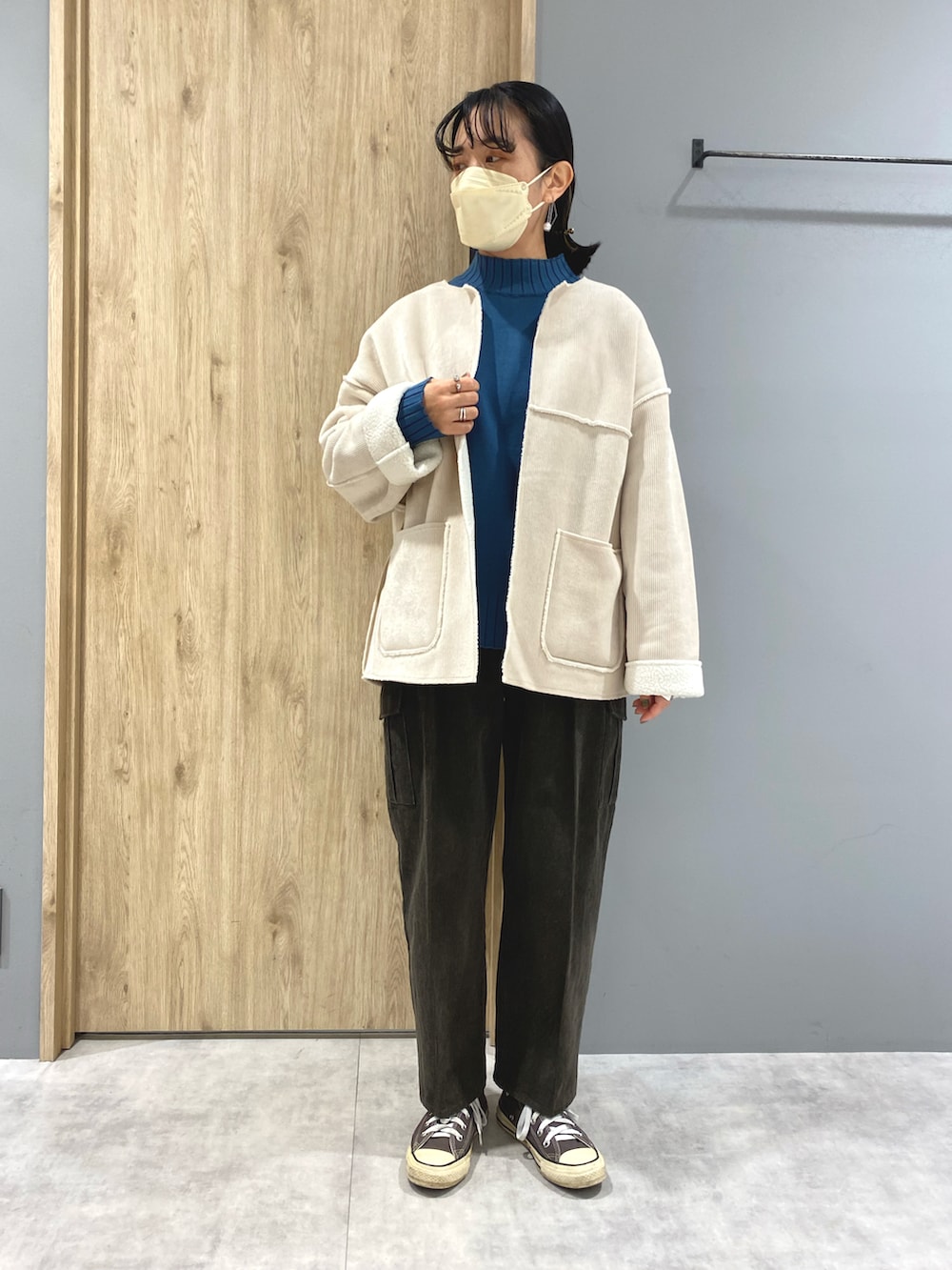 ブラウン系のパンツ、ホワイト系のノーカラージャケット、ブルー系のニット/セーターを着用したレディースの冬コーディネートの2枚目の写真