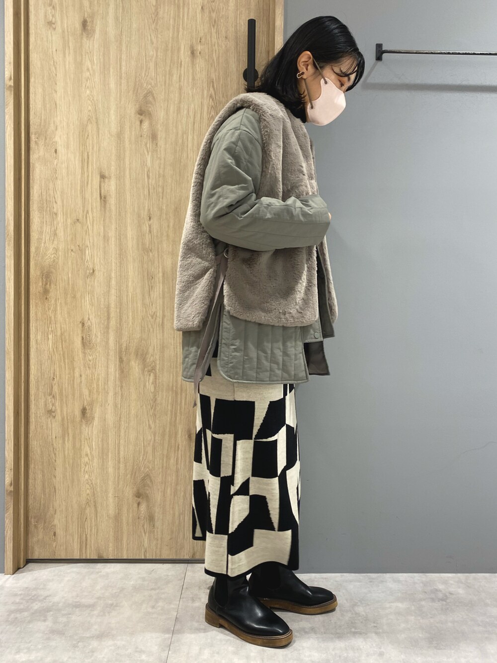 グリーン系のジャケット/アウター、ブラック系のニット/セーター、ブラック系のスカートを着用したレディースの秋コーディネートの2枚目の写真