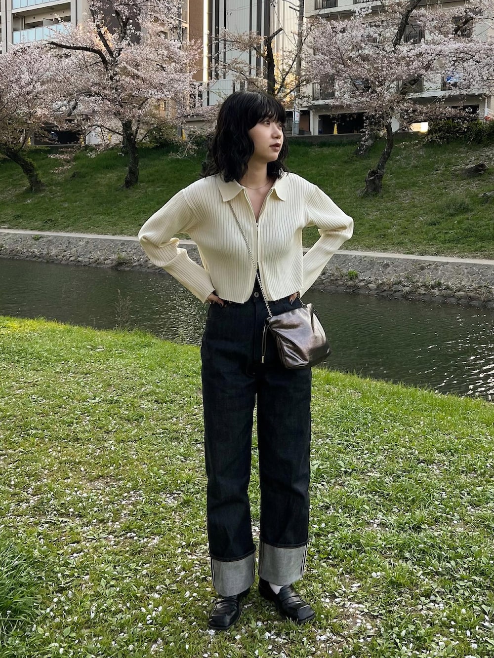 ホワイト系のニット/セーター、ブルー系のデニムパンツ、シルバー系のショルダーバッグを着用したレディースの春コーディネートの4枚目の写真