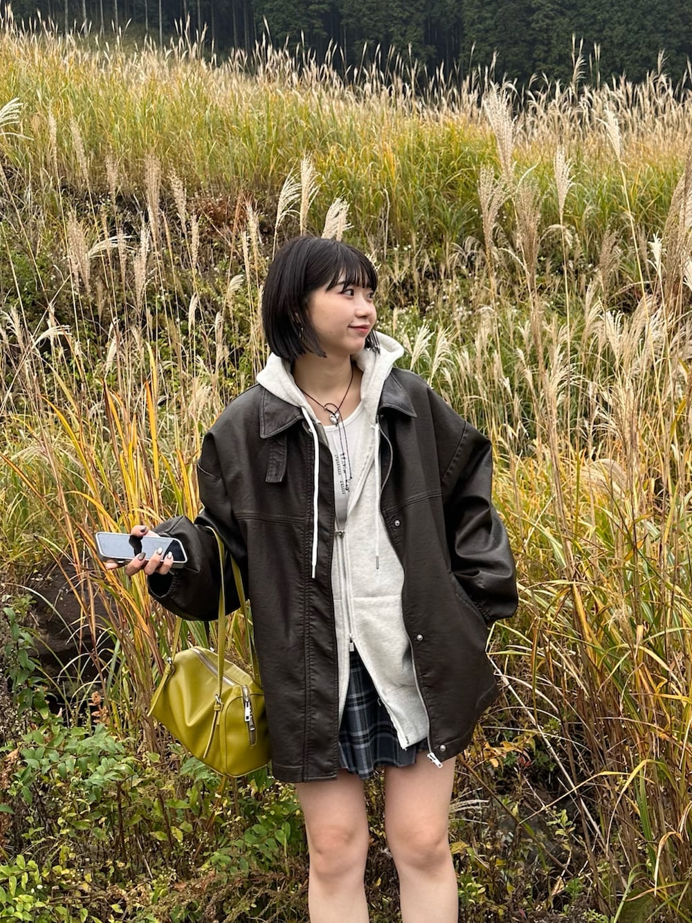 グレー系のパーカー、グレー系のスカート、ブラック系のブーツを着用したレディースの秋コーディネートの3枚目の写真